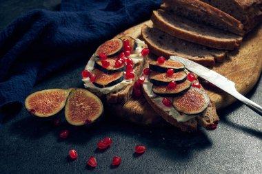 Masa kahvaltısında peynirli çavdar ekmeği, incir ve nar dilimleri.