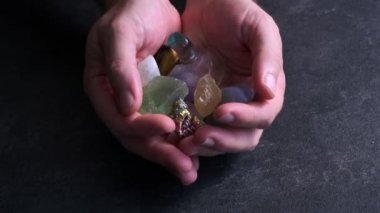 Siyah arka planda farklı değerli taşları olan bir erkek eli.