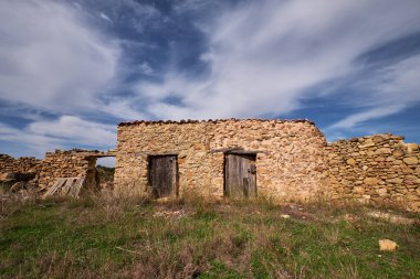 Bulutlu gökyüzüne karşı eski bir taş evin kalıntıları.