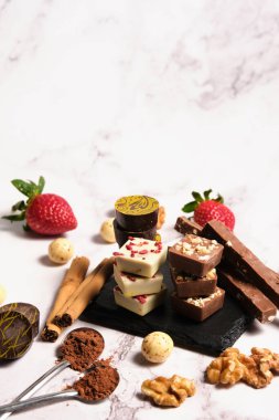 çeşitli çikolatalar koyu ve beyaz çikolata ve açık mermer arka planda çilekler.