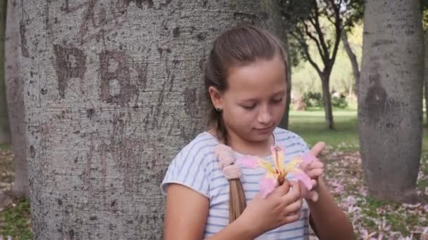 Mała Dziewczynka Gapiąca Się Kwiat Przy Drzewie Parku Zwolnionym Tempie — Wideo stockowe