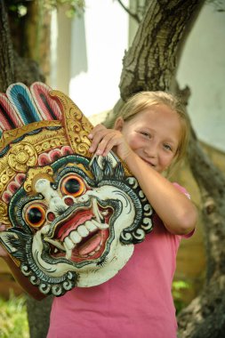 Küçük kız bahçede Endonezya maskesiyle oynuyor.
