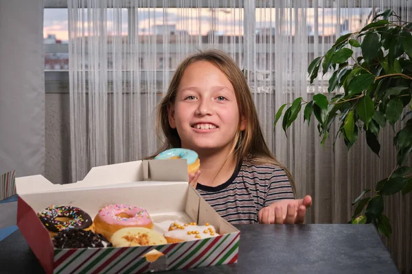 a little girl with a box of donuts chooses which one to eat