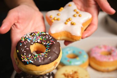 two donuts with chocolate and multi-colored sprinkling in a womans hand