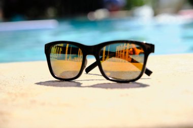 Mavi havuz suyunun arka planında güneş gözlüğü