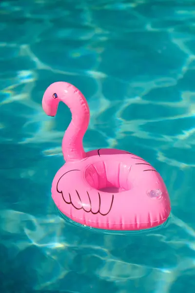 inflatable pink flamingo toy swims in blue water pool