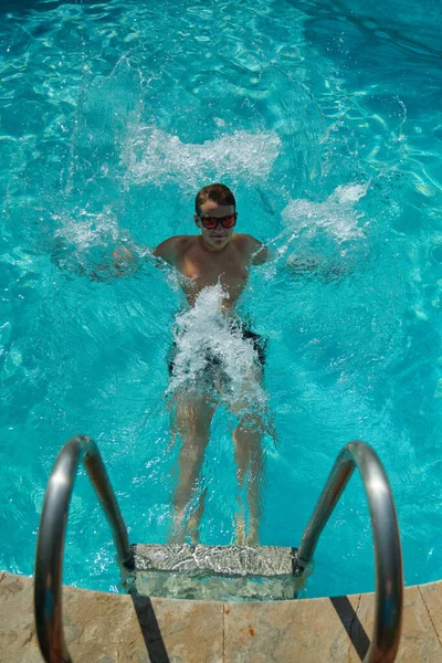 男孩在蓝色的游泳池里游泳 — 图库照片