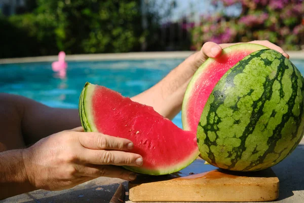 a piece of watermelon in your hand in the pool