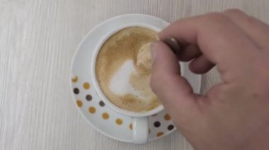 Bir adamın kahvesini fincanda karıştırırken yakın plan görüntüsü.