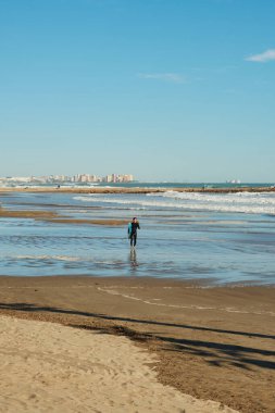 Sahilde sörf tahtası olan yalnız bir sörfçü.