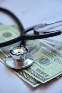 Tıbbi steteskop ve para. Masada birkaç dolar var.