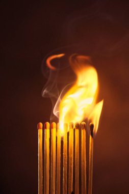 Bir sıra kibrit koyu bir arka planda alevler içinde kaldı.