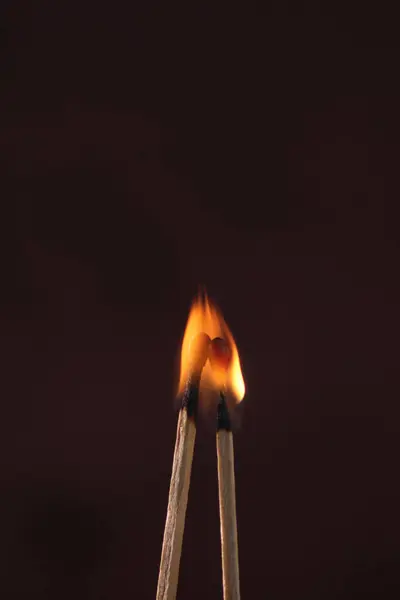 two lighted matches engulfed in flames on a dark background