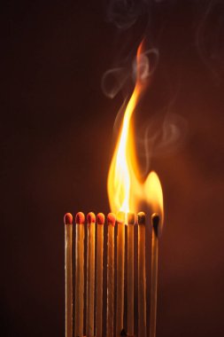 Bir sıra kibrit koyu bir arka planda alevler içinde kaldı.