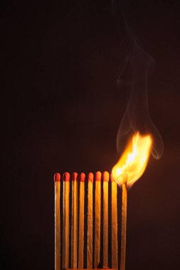 Bir sıra kibrit koyu bir arka planda alevler içinde kaldı.