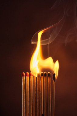 Bir sıra kibrit koyu bir arka planda alevler içinde kaldı.