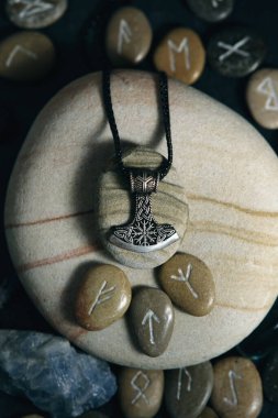 Thor 'un el yapımı taşlarla çevrili gümüş renkli tılsımlı çekici.