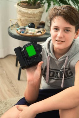 Beyaz arka planda elinde kamera olan bir çocuğun portresi.