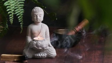 Duman tüten Palo Santo 'nun yanındaki karanlık arka planda Buda' nın taş heykeli.