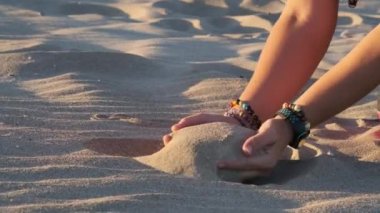 Kumsalda kumlara dokunan kadın parmaklarından dökülen kum.