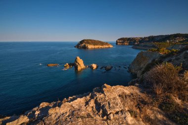 Yaz mevsimi kayalık koy sakin mavi deniz ve berrak gökyüzü
