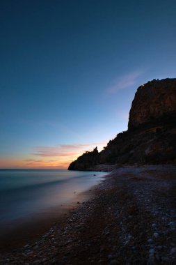 İspanya 'da gün batımında deniz manzaralı kayalık plaj