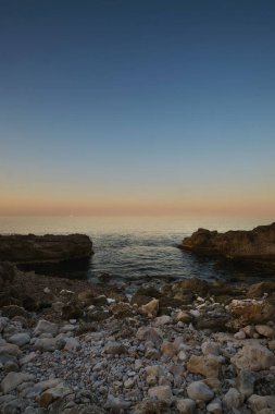 İspanya 'da gün batımında deniz manzaralı kayalık plaj