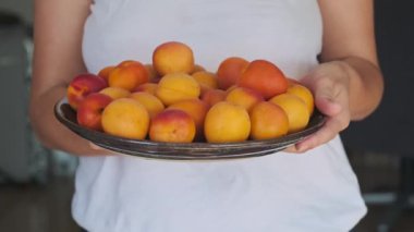 Bir tabak olgun, iştah açıcı sarı kayısısı olan bir kız.