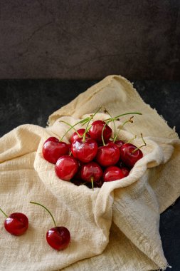 Küçük bir kase kirazda, masanın üstünde birkaç tane böğürtlen var.