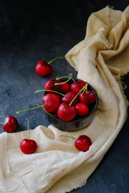 Küçük bir kase kirazda, masanın üstünde birkaç tane böğürtlen var.