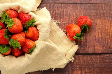 Tahta arka planda izole edilmiş kırmızı olgun çilek kasesi.