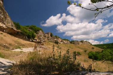 Gökyüzünün arka planında beyaz bulutlar, patikalı dağlar...