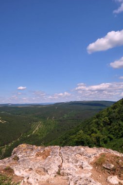 Gökyüzünün arka planında beyaz bulutlar, patikalı dağlar...