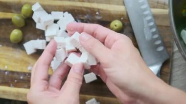 Tahtada Feta peyniri küpleri ve yeşil zeytin ve bıçak.