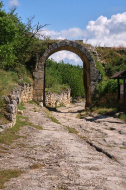 Parlak mavi bir gökyüzünün altında yemyeşil yemyeşil ile çevrili tarihi bir yola açılan antik bir taş kemer yolu. Yıpranmış taş duvarlar ve engebeli yollar tarih ve keşif duygusunu çağrıştırıyor..