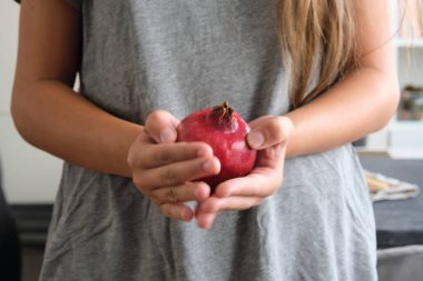 Bir kızın ellerinde olgun kırmızı bir nar meyvesi.