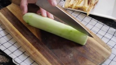 Kesme tahtasındaki taze salatalık dilimlere ayrılır.