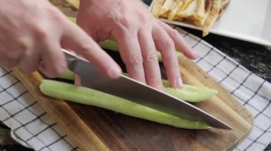 Kesme tahtasındaki taze salatalık dilimlere ayrılır.