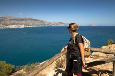 Sırt çantasıyla yüksek kıyıda duran genç bir kadın.