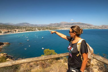 Sırt çantasıyla yüksek kıyıda duran genç bir kadın.