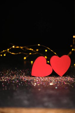 Karanlık bir arka planda, ışıkların ışığında, iki kalp yan yana.