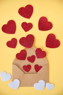 Sarı arka planda farklı boyutlarda kırmızı kalpler.