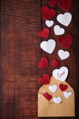 Beyaz ve kırmızı kalpler ahşap bir arka planda uçar.