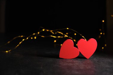 Karanlık bir arka planda, ışıkların ışığında, iki kalp yan yana.