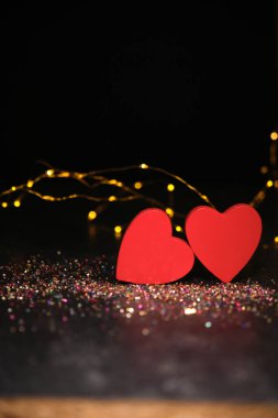 Karanlık bir arka planda, ışıkların ışığında, iki kalp yan yana.