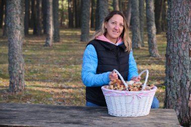 Sonbahar ormanında bir sepet dolusu mantarı olan bir kız.