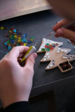 Çocuk bir tahta parçasına çok renkli gözlük yapıştırıyor.