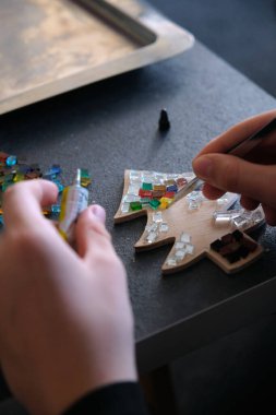 Çocuk bir tahta parçasına çok renkli gözlük yapıştırıyor.