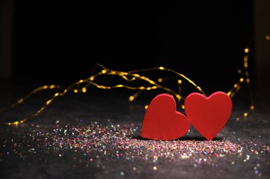 Karanlık bir arka planda, ışıkların ışığında, iki kalp yan yana.