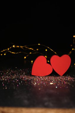 Karanlık bir arka planda, ışıkların ışığında, iki kalp yan yana.